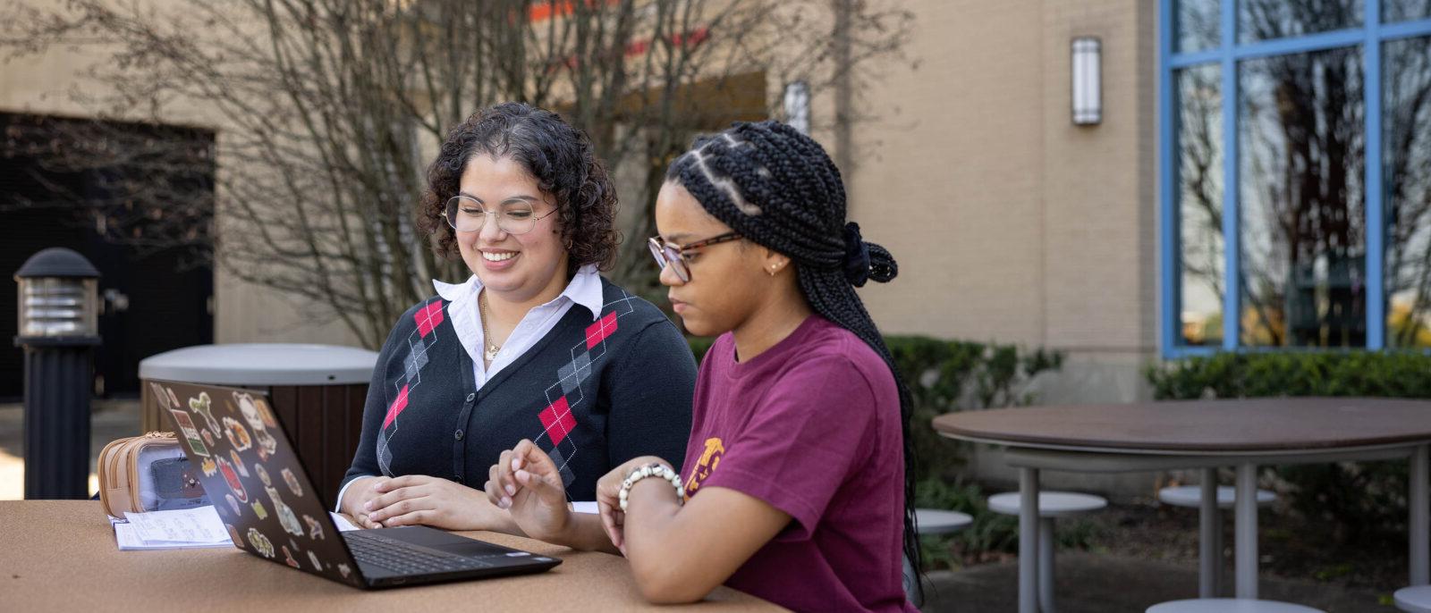 Female students working on laptop outside